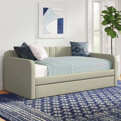 a day bed with pillows on top of it in front of a blue and white rug