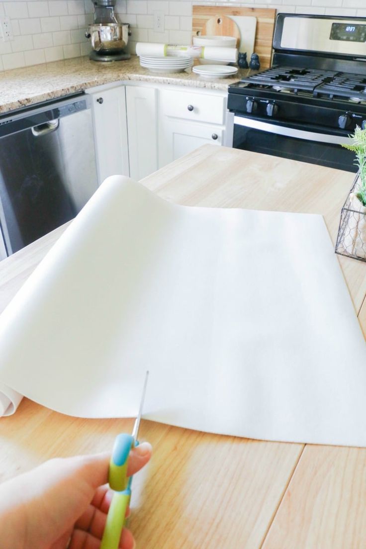 a person holding a toothbrush in front of a piece of paper on a table