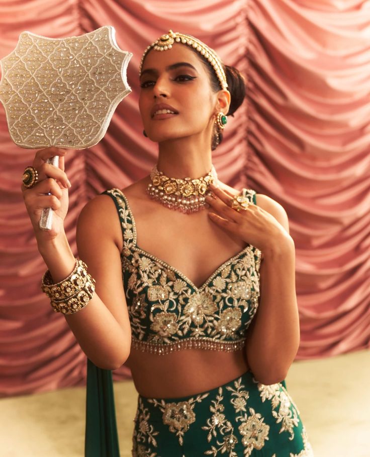 Capture attention in this emerald green embellished blouse with an attached dupatta, paired with a lehenga featuring cancan for dramatic flair. The intricate embellishments and elegant draping create a stunning ensemble, perfect for weddings and festive celebrations where you want to make a memorable entrance. Green Choli For Reception With Traditional Drape, Green Gown With Unstitched Blouse For Party, Glamorous Green Choli With Mirror Work, Green Lehenga With Sheer Dupatta In Traditional Drape, Green Lehenga With Sheer Dupatta, Glamorous Green Lehenga, Glamorous Green Choli For Wedding, Glamorous Green Wedding Choli, Elegant Green Lehenga With Sheer Dupatta