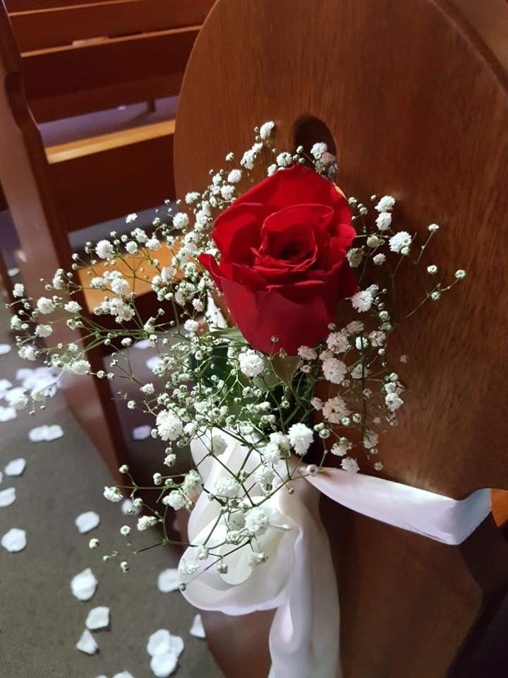 a red rose sitting on top of a wooden chair next to baby's breath