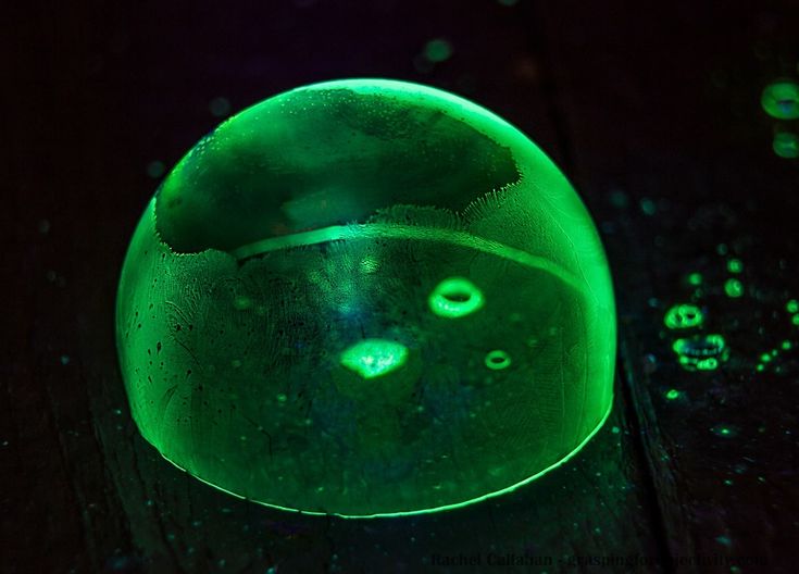 a green object sitting on top of a wooden table next to water droplets and drops