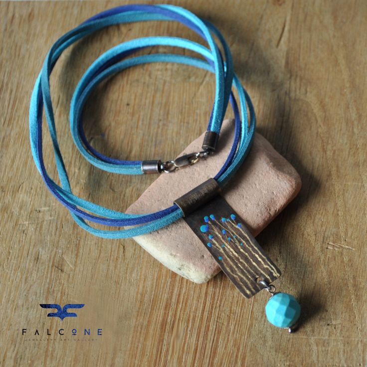 Necklace in tones of blue, turquoise green and cool sapphire. The triple vegan strap has intense colors of intertwined sapphire, turquoise and pure blue. It forms the base for a pendant made of brass patinated to walnut brown, decorated with engraved, subtle flower stems and enamel colors of blue with a touch of turquoise. The bottom of the pendant is decorated with a natural ball of turquoise with fine faceting. The whole set in tones of brass and dark silver. Clasp of lobster pincers type.  Size of the pendant:  Length - 4 cm (ca. 1.57in); width - 1,5 cm (ca. 0.59in).  The diameter of the stone is 12 mm (ca. 0.47in).  The length of the pendant with the stone is 6 cm (ca. 2.36in).  The length of the whole necklace with clasp is 47 cm (ca. 18.5in). falcOneGALLERY Newsletter ❤️ Join our new Blue Enamel Bohemian Necklaces, Bohemian Turquoise Hand Painted Jewelry, Turquoise Bohemian Hand Painted Jewelry, Artisan Turquoise Necklace With Adjustable Cord, Blue Brass Pendant Jewelry, Turquoise Jewelry With Adjustable Cord As Gift, Blue Metal Amulet Jewelry, Bohemian Blue Turquoise Necklace With Patina, Blue Patina Necklace Perfect For Gifts