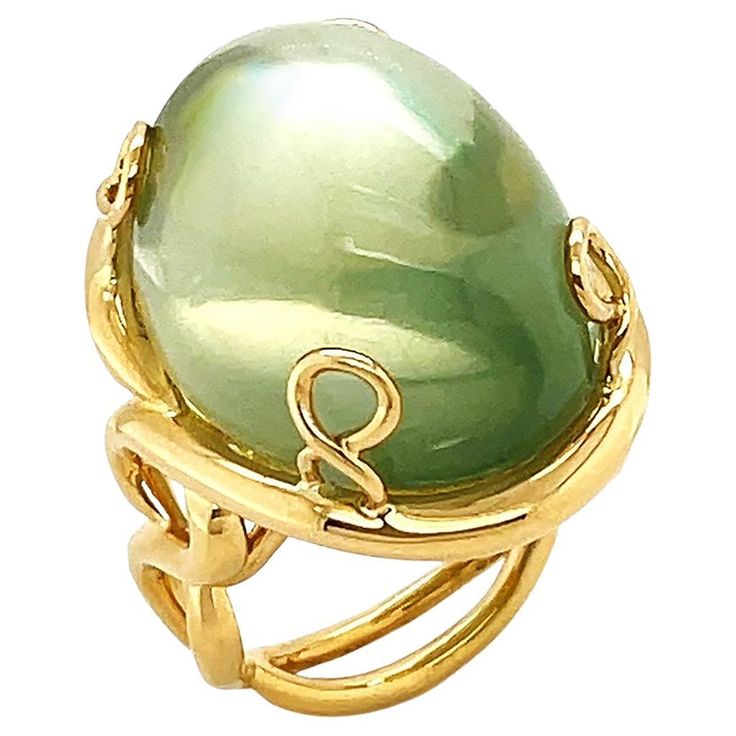 Synonymous with its name, a significant size of moonlit gemstone in everyday design serves as a timeless jeweled piece. Adularescence glows within this ring, an effect that resembles the appearance of a shimmering moon. The featured jewel is a mango moonstone with beautiful shades of green, mainly neutral sage, fashioned into an oval cabochon. When light strikes the surface of a gemstone, it exhibits a floating sheen like the moon. Depending on the angle, it also displays an attractive light and shades. The moonstone is set between four pieces of twisted 18k yellow gold woven into prongs. Underneath is a double shank that stretches like vines. The weight is 34.9 carats of moonstone. The ring measures 0.85 inches (width) by 1.06 inches (length) by 1.34 inches (height) by 0.59 inches (depth) Moonstone Ring, Oval Cabochon, Shades Of Green, Fashion Rings, Moonstone, The Moon, Vines, Vintage Jewelry, Jewelry Rings