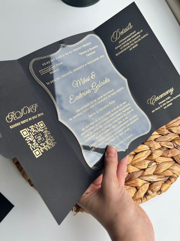 a person holding an open black and gold wedding program book in front of a basket