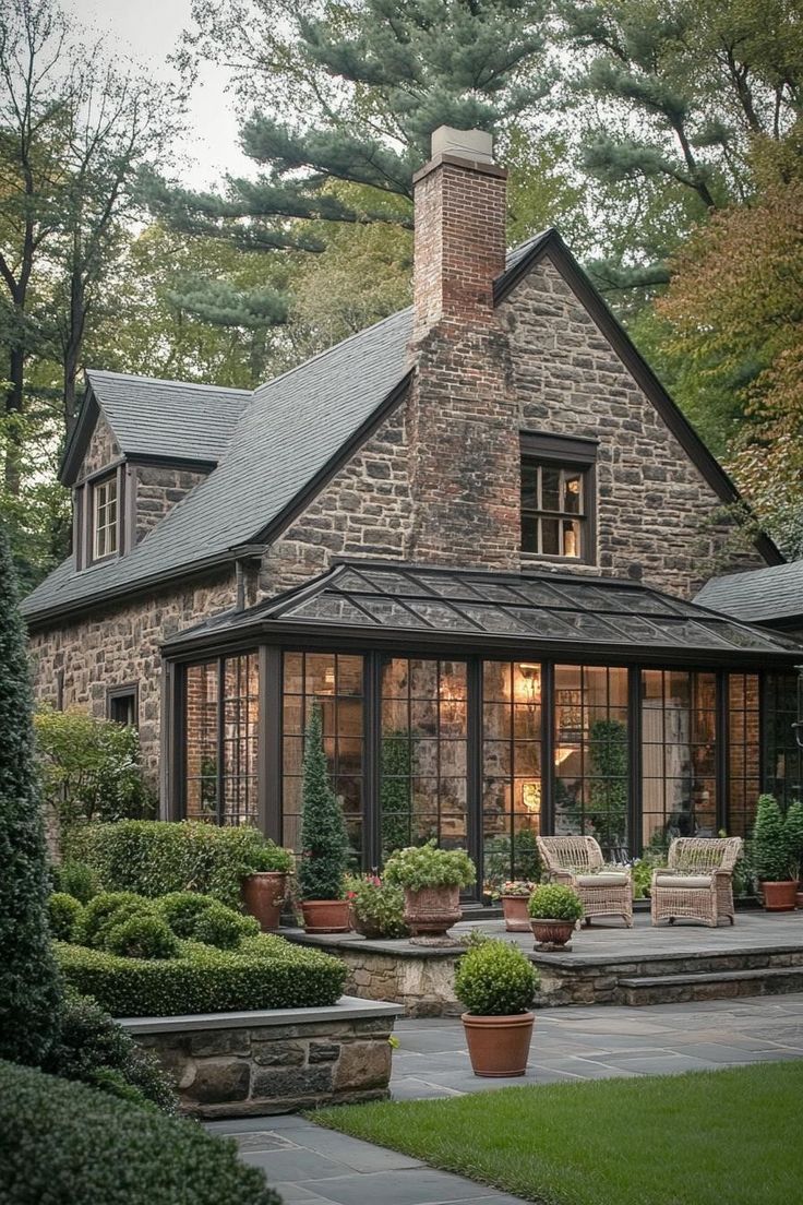 a stone house surrounded by greenery and potted plants