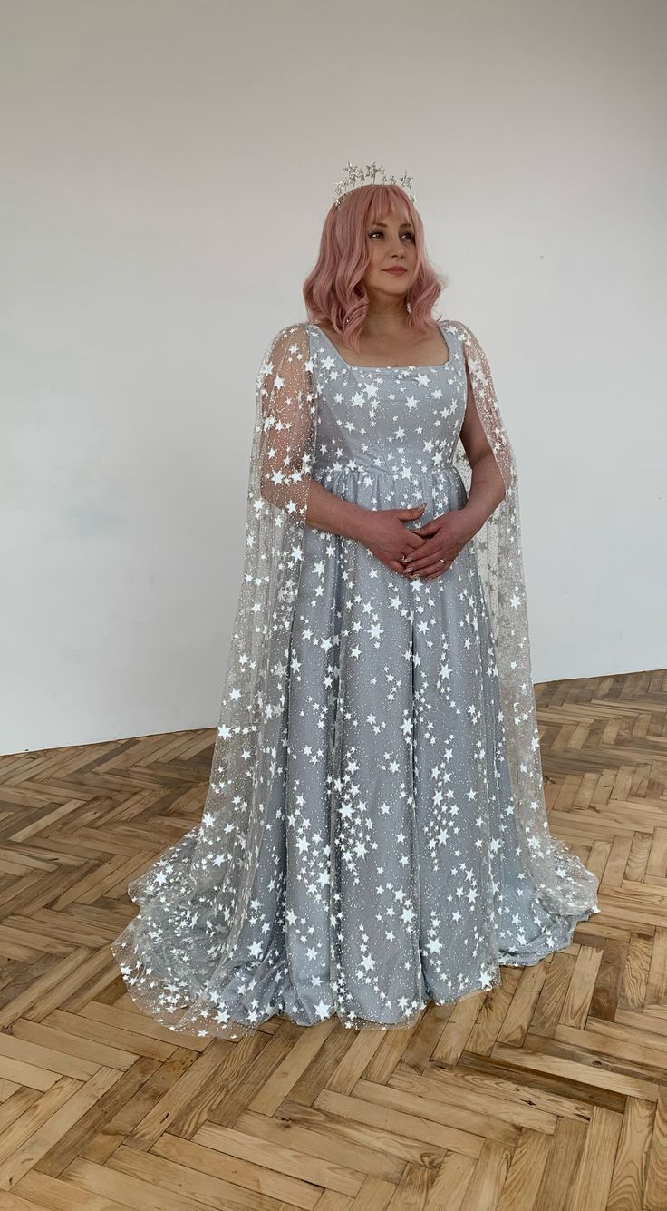 a woman with pink hair wearing a white dress and standing on a wooden floor in front of a wall