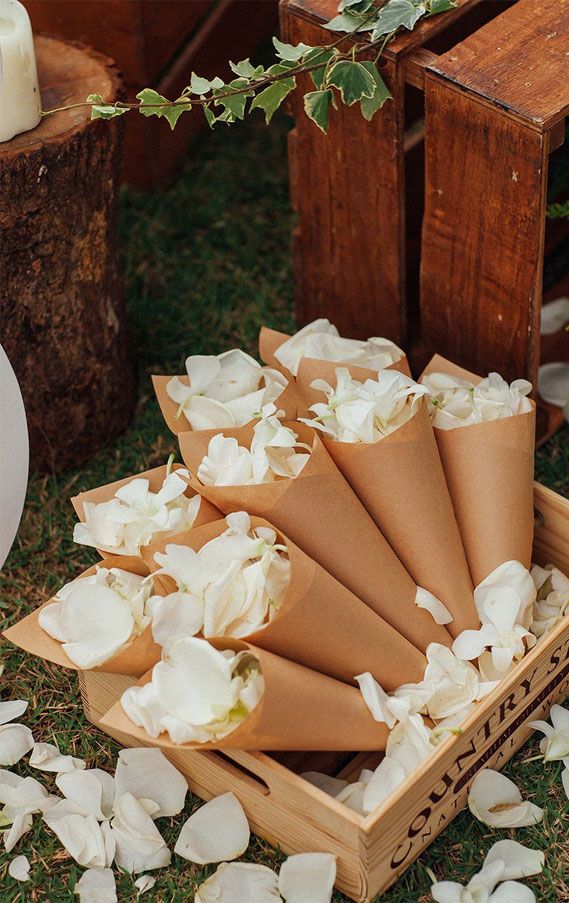 there are many flowers that are in the wooden box on the grass and petals all over the ground