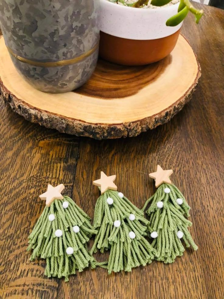 three small green christmas trees are sitting on a wooden table next to a potted plant