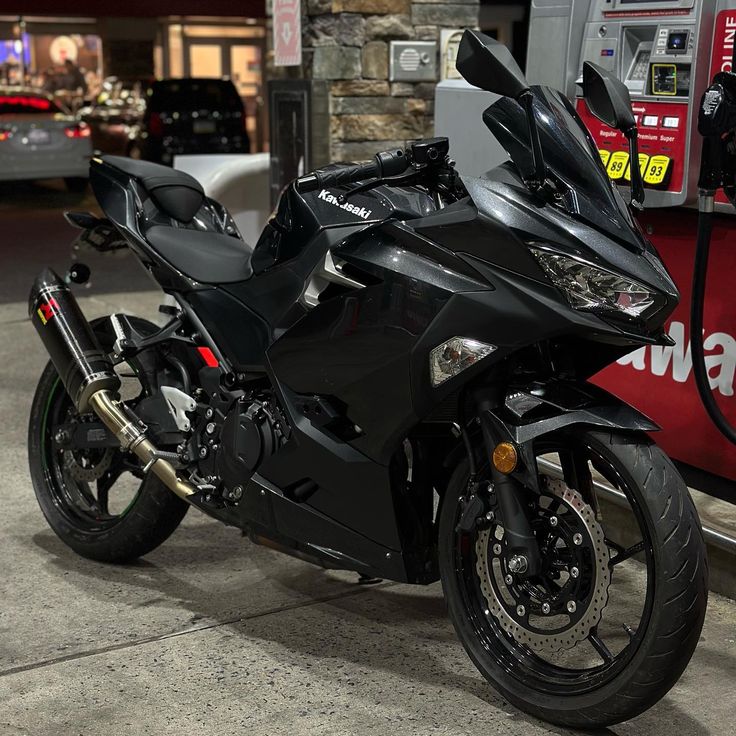 a black motorcycle parked next to a gas pump