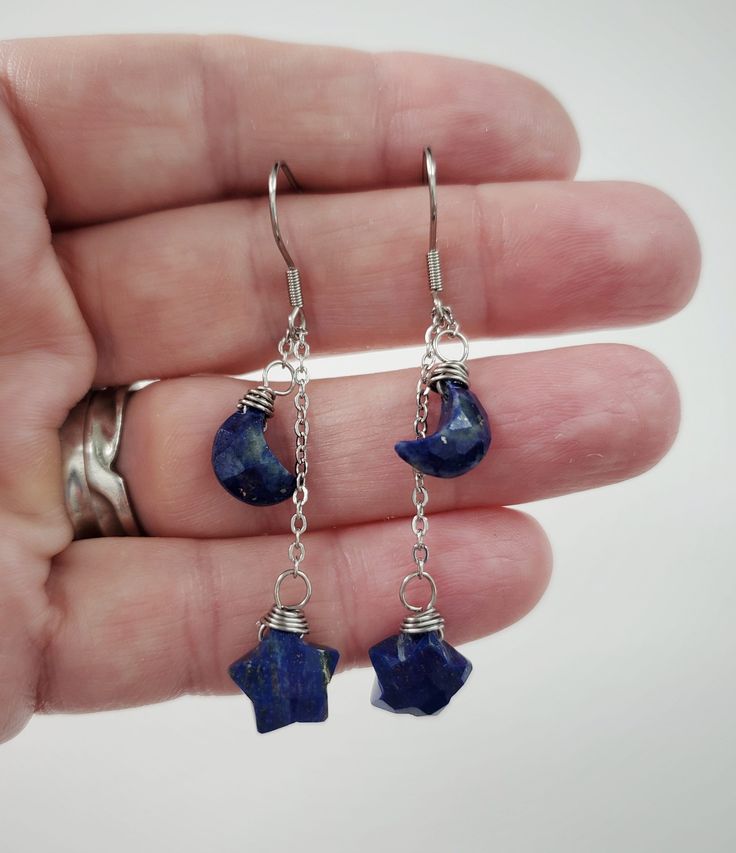 "These genuine moon and star shaped Lapis Lazuli stones are simply wrapped with 24 gauge stainless steel wire and dangle by stainless steel chain. 100% stainless steel earring hooks. They hang from an adjustable 1.25\" stainless steel chain, so you can switch up the length between the stones.  The earrings will come on an earring card with silicone earring backs, and packaged in a charming box, perfect for easy gifting! Lapis Lazuli is a deep blue metamorphic rock used as a semi precious stone t Celestial Dangle Earrings With Star Charm, Celestial Style Dangle Earrings With Star Charm, Handmade Celestial Dangle Earrings, Celestial Drop Earrings With Star Charm, Celestial Dangle Earrings For Gift, Celestial Moon Charm Dangle Earrings, Celestial Dangle Earrings With Moon Charm, Blue Dangle Earrings With Moon Charm, Crescent Earrings With Star Charm As Gift