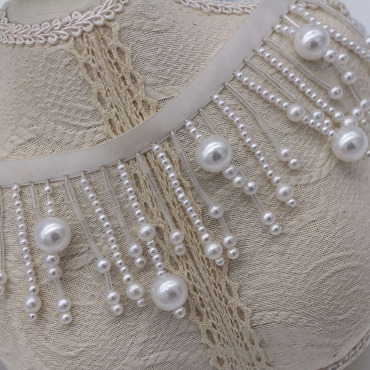 a white dress with pearls and lace on it