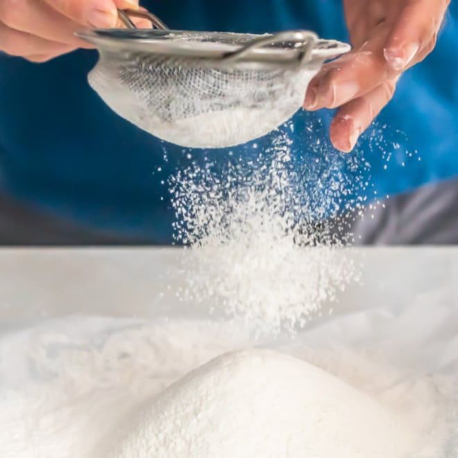 a person scooping sugar out of a bowl