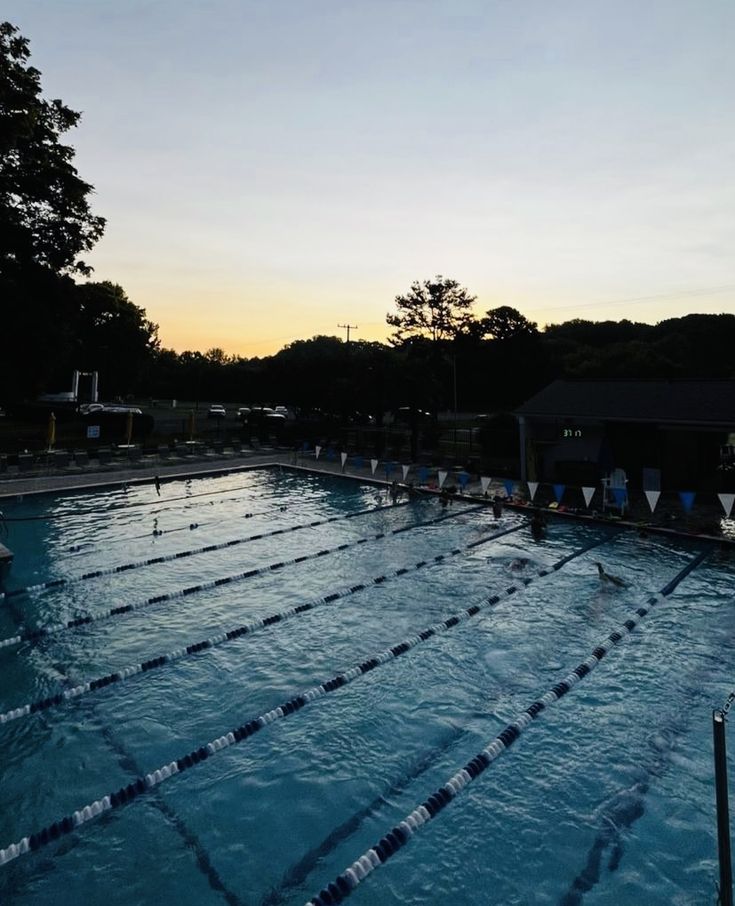 an empty swimming pool at dusk with no people in it and the sun going down