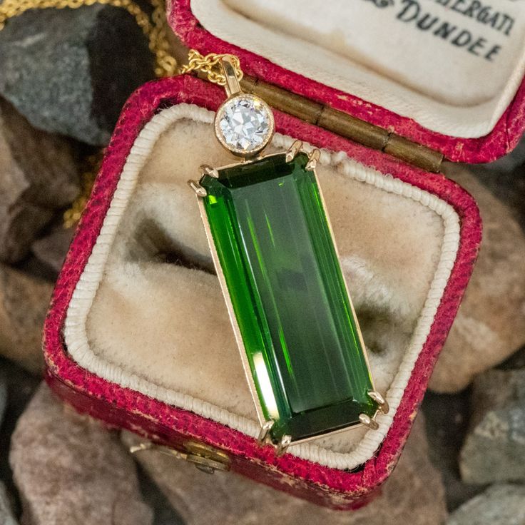 This classy pendant is accented with one (1) octagonal step cut natural green tourmaline set into a four-prong setting and is topped with one (1) old European cut diamond set into b bezel setting that is bordered with milgrain edging. The pendant measures 31.0mm X 10.4mm and is suspended from a 14K yellow gold neck chain measuring 16 inches in length. Classic Green Tourmaline Jewelry, Elegant Emerald Cut Tourmaline Jewelry, Elegant Baguette-cut Tourmaline Jewelry, Elegant Baguette Cut Tourmaline Jewelry, Formal Green Tourmaline Necklace, Classic Tourmaline Jewelry For May Birthstone, Formal Tourmaline Birthstone Jewelry, Emerald Cut Tourmaline Jewelry Gift, Art Deco Green Jewelry With Bezel Setting