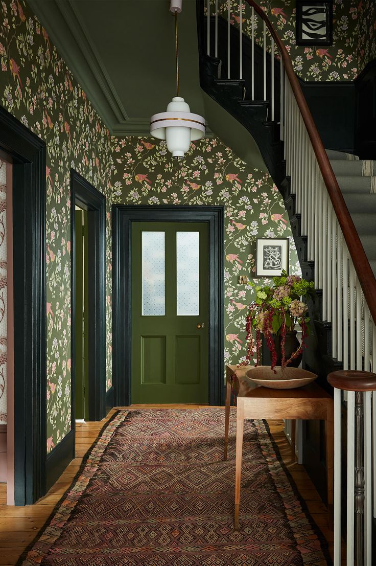 an entryway with green door and floral wallpaper on the walls next to stairs