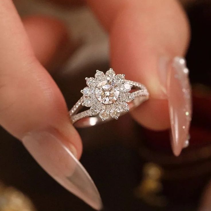 a woman's hand holding a diamond ring on top of her finger, with other jewelry in the background