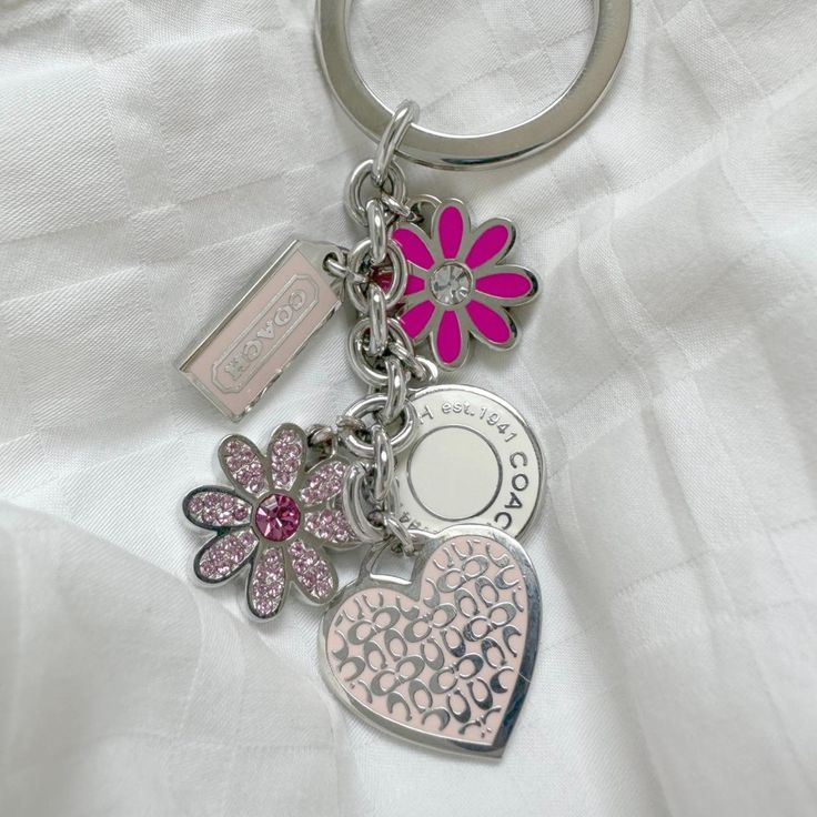 a pink and white heart shaped keychain with two charms attached to it's sides