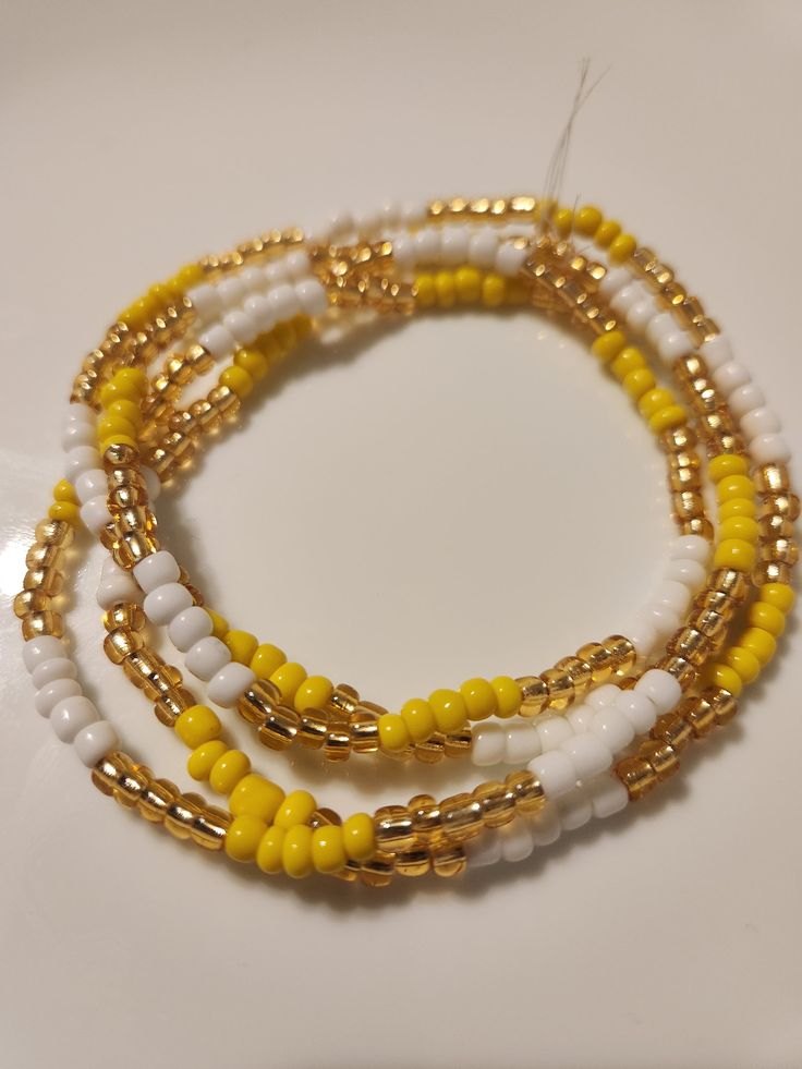 "Ochun/Ochún(Oshún) Santeria Bead Necklace, Collares, Eleke ,Elekes Collares, Eleke Necklaces, Yoruba Religion, Santeria, Ifa, Orisha, Ekes, Orisha Necklace Length vary from 14\" - 17\" Made from glass seed beads Made with yellow, white, and gold beads, in sets of 5 Items sold are not washed or blessed." White Beaded Chain Bracelets For Summer, White Beaded Necklace With Gold Beads For Summer, Gold Beaded Chain For Summer, Tiny Yellow Beads For Summer, White Necklaces With Gold Beads For Summer, White Beaded Bracelets With Gold Beads For Beach, White Beaded Necklaces With Gold Beads For Beach, Yellow Beaded Bracelets With Large Beads For Beach, Handmade Gold Beads For Summer