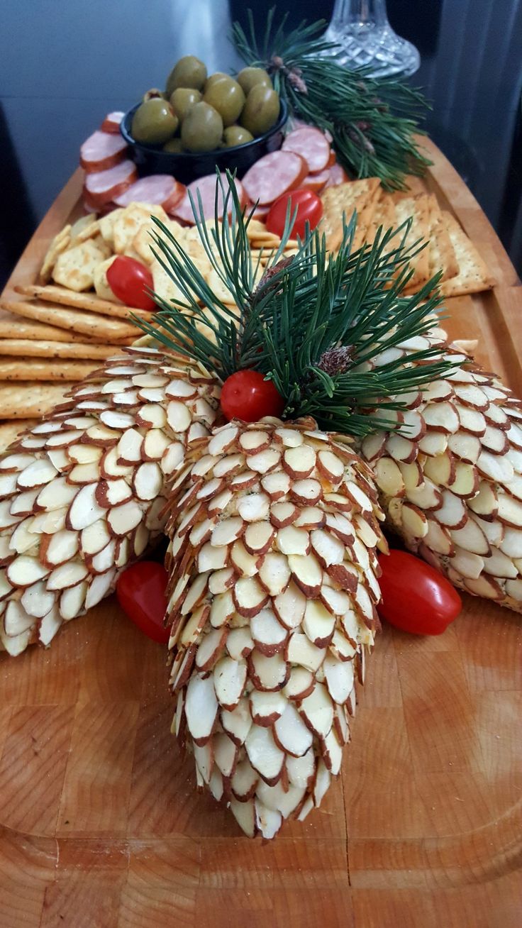 pine cones, tomatoes and olives are arranged on a platter with crackers