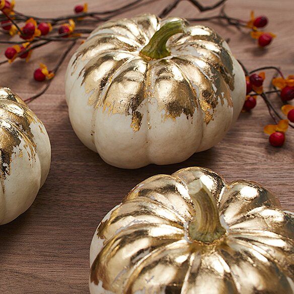 three white pumpkins sitting on top of a wooden table