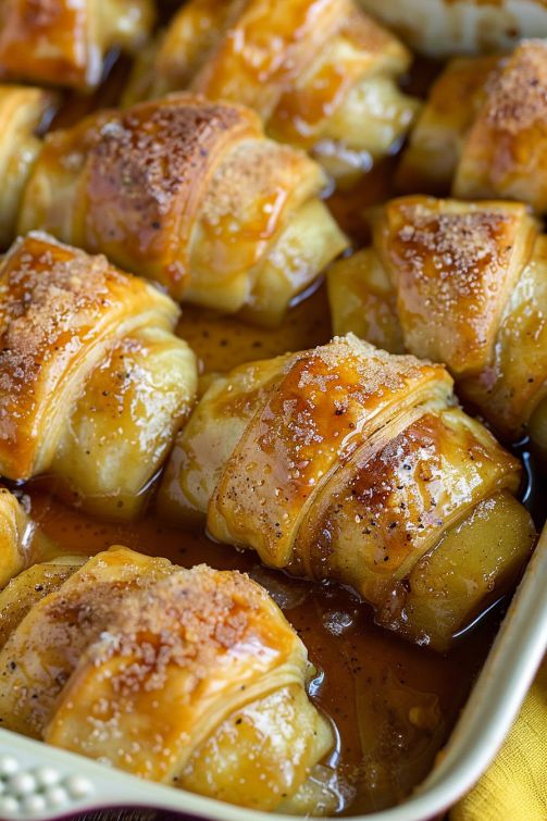 baked pastry items in a baking dish covered with caramel sauce and flecks