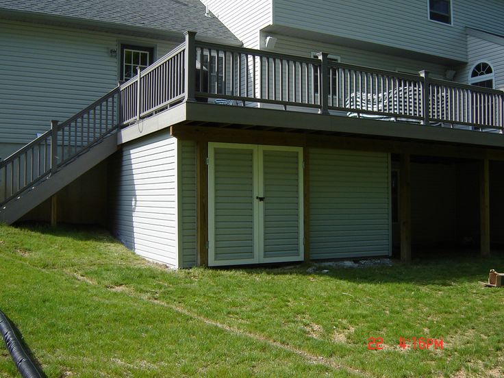 the back side of a two story house with an attached deck and stairs leading up to it