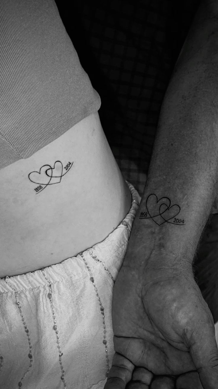 two hearts with arrows tattoo on the left side of the stomach and right hand in between them