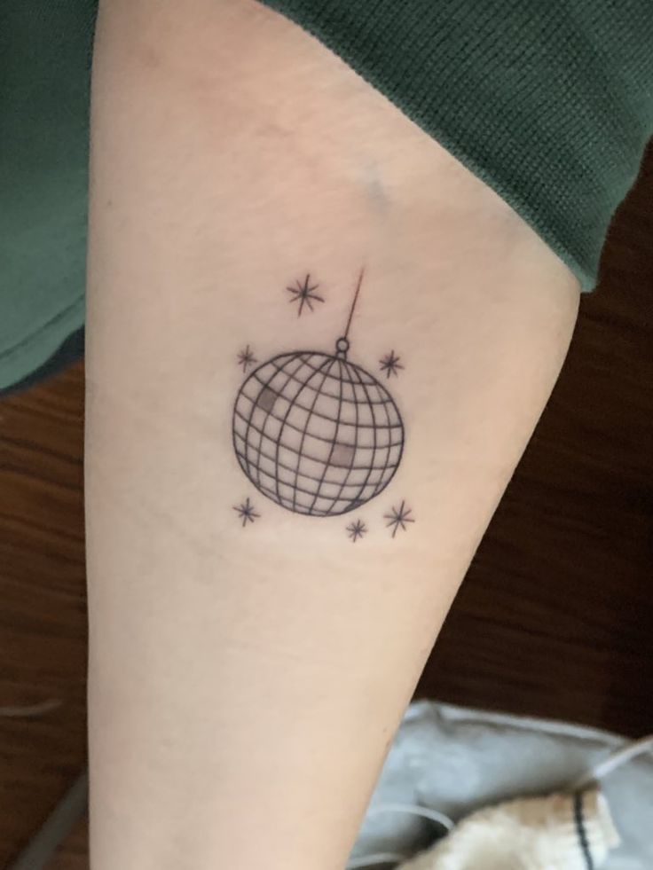 a person with a small tattoo on their arm that has a globe and stars around it