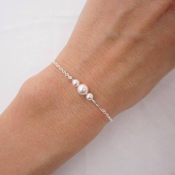 GENUINE STERLING SILVER - A GREAT KEEPSAKEThis dainty pearl bracelet is made using sterling silver chain and a sterling silver lobster clasp. Two 4mm Swarovski pearls are placed on either side of a 6mm center pearl (available in your choice of 5 colors). Comes in a gift box, perfect for gift giving. SIZING - IMPORTANT: To determine bracelet size, measure around your wrist and add 1/2 inch to get your bracelet size. Minimal Bracelet Silver, Small Silver Bracelets, Jewelry To Sell, Dainty Pearl Bracelet, Wedding Jewellry, Bridesmaid Pearl Bracelet, Swarovski Pearls Bracelet, Bracelets Pearl, Bridal Bracelet Pearl