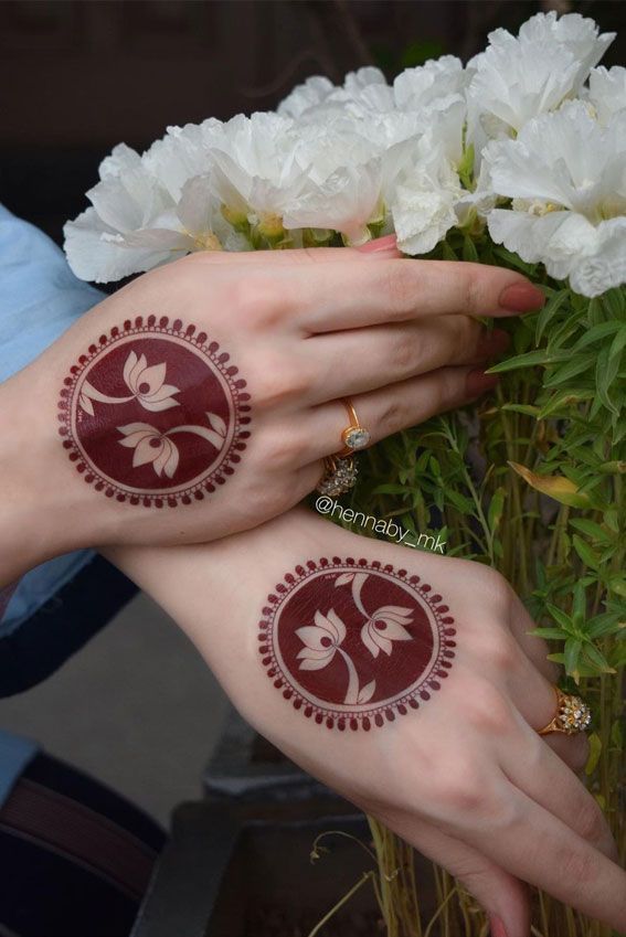 two hands with henna tattoos on their palms and white flowers in front of them