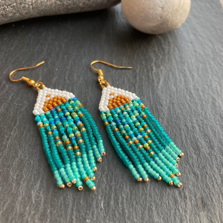 two pairs of beaded earrings sitting on top of a table