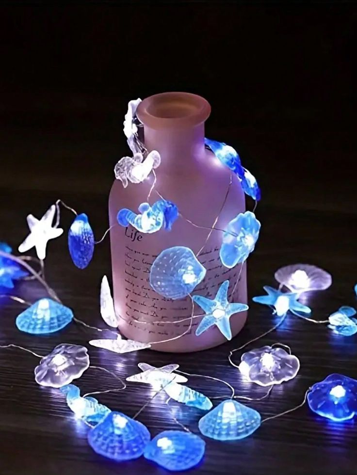 a bottle with blue lights on it sitting on a wooden table next to a string of stars