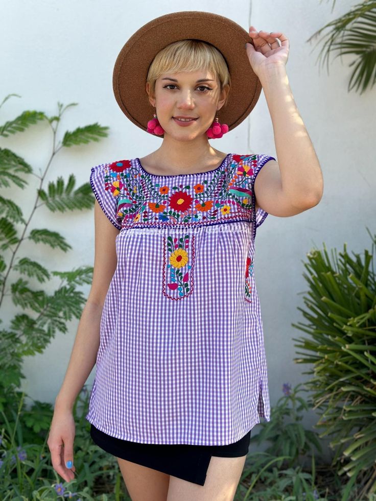 "Purple gingham summer blouse, checkered Mexican top, hand embroidered flowers, short sleeve shirt, boho hippie fashion, tropical destination Elevate your summer wardrobe with our Purple Gingham Summer Blouse, a charming blend of casual elegance and boho hippie fashion. This checkered Mexican top is designed for those seeking a touch of artistry in their everyday style. Crafted with love, it features intricate hand-embroidered flowers that transform it into a wearable masterpiece. The short sleeves of this blouse make it a versatile choice for warm, tropical destinations or casual outings. Picture yourself strolling along a sun-kissed beach or sipping cocktails at a seaside café, and you'll understand the allure of this vibrant top. The purple gingham pattern adds a playful touch to the bl Summer Blouse With Floral Embroidery And Short Sleeves, Summer Plaid Top For Beach, Spring Bohemian Embroidered Short Sleeve Top, Casual Short Sleeve Embroidered Summer Top, Plaid Short Sleeve Top For Summer, Summer Gingham Blouse For Picnic, Summer Plaid Blouse For Picnic, Bohemian Short Sleeve Top With Multicolor Embroidery, Plaid Short Sleeve Beach Top