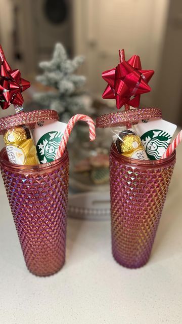 two red glass cups with candy canes and starbucks's christmas decorations in them