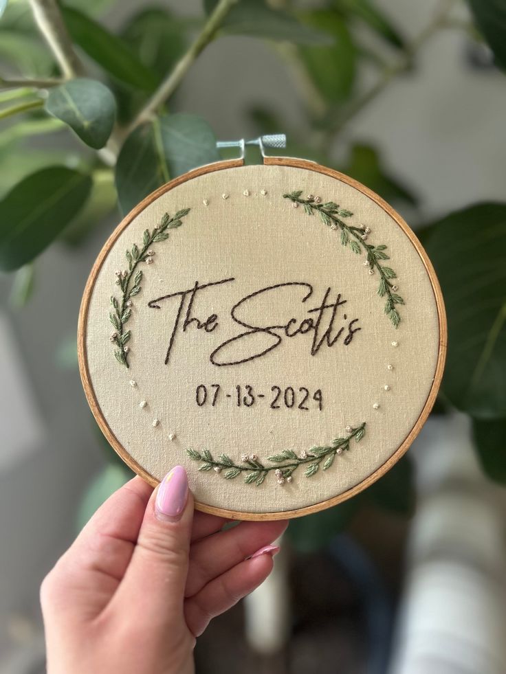 a person holding up a small embroidered hoop with the words, the scotts on it