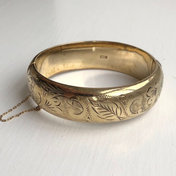 A Vintage bangle displaying beautiful leaf engravings. The wonderful warm yellow gold colour really shows off the detailing perfectly. CONDITION: Wear consistent with age and use. Please see photos for more detail. Strong clasp.  HALLMARKED SILVER, ASSAYED IN BIRMINGHAM 1970 BAND WIDTH: 18mm APPROX. INTERNAL MEASUREMENT (AROUND): 175mm APPROX. DIAMETER (INTERNAL): 55mm x 60mm WEIGHT: 24.4 grams ) Engraved Bangle Bracelet, Engraved Bangle, Vintage Bangles, Warm Yellow, Gold Colour, Gold Bangles, Cute Jewelry, Bangle Bracelet, Vintage Silver