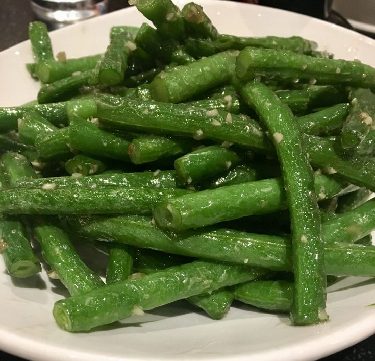 a white plate topped with green beans covered in seasoning