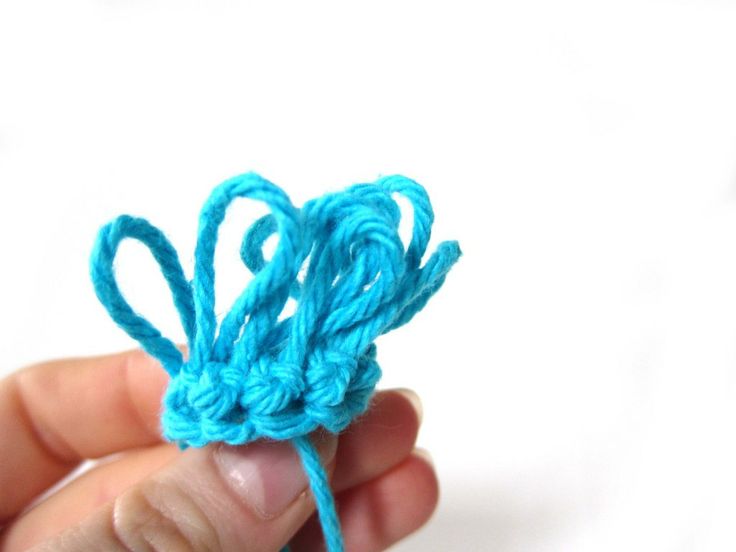 a hand holding a piece of blue yarn in it's left hand and the end of the string is crocheted