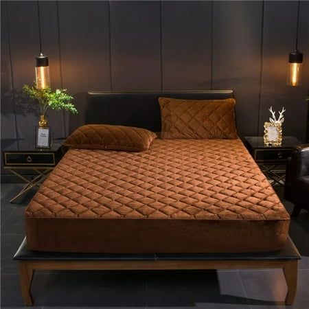 a bed that is made up with brown sheets and pillows on top of the bed