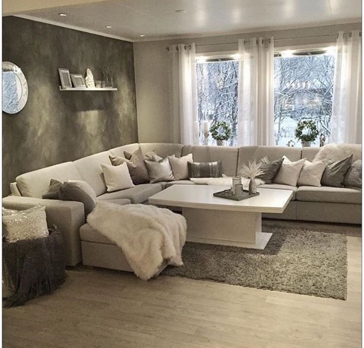 a living room filled with lots of furniture next to a window covered in white curtains