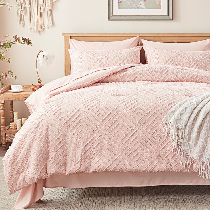 a bed with pink comforters and pillows in a bedroom