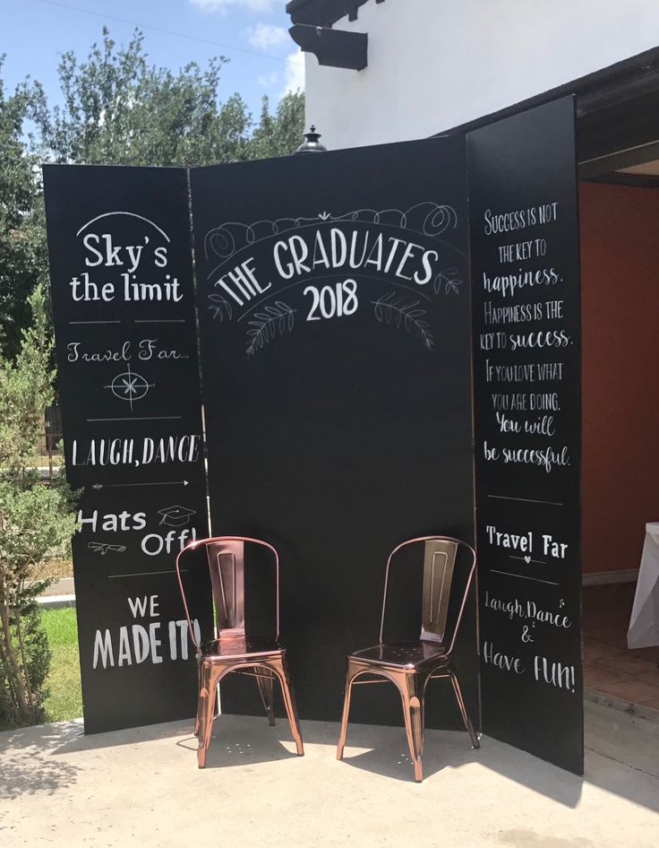 two chairs sitting on top of a sidewalk next to a blackboard sign that says sky's the limit