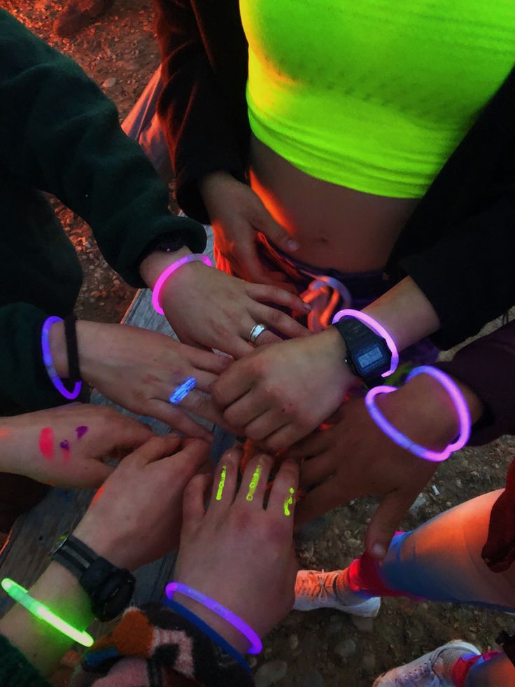 a group of people standing around each other with their hands in the air and glowing bracelets