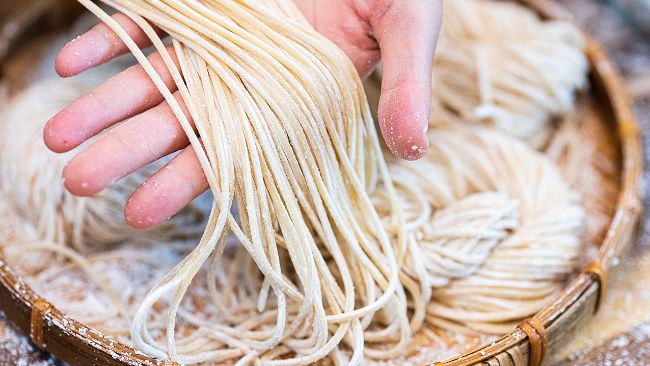 a person is picking up some noodles from a bowl