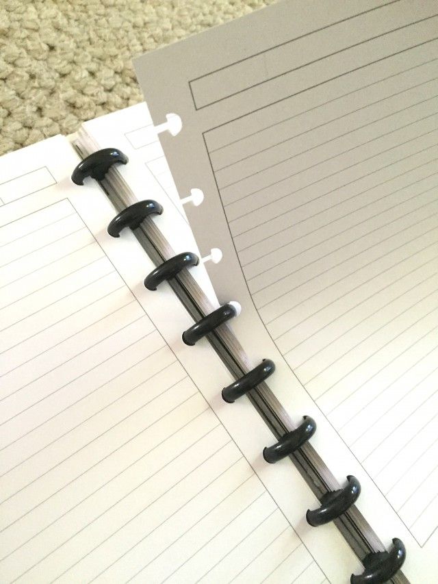 an open notebook with black spirals on top and white paper attached to the cover