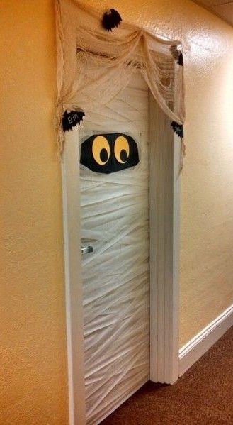 an open door decorated to look like a ghost with eyes and mouth hanging from it