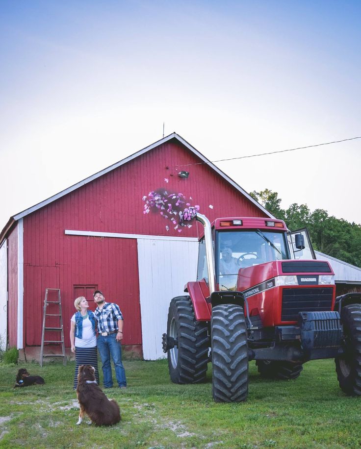 a man and woman standing in front of a tractor with a dog next to it