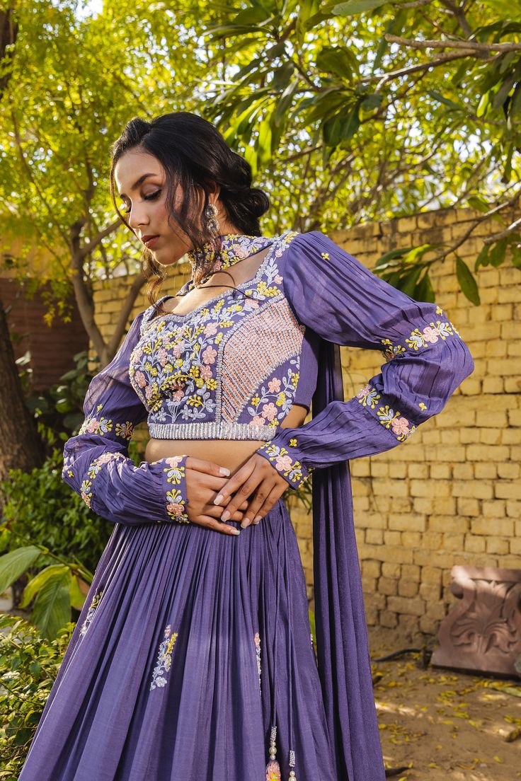 Make a statement with the Suruchi Parakh Lavender Crepe Embroidered Lehenga Set! This gorgeous lehenga set is perfect for any special occasion, from weddings to parties.
The lehenga features a lavender crepe base with intricate pearl and thread embroidery. The delicate details create a stunning pattern that will catch everyone’s eye. The matching blouse is also embroidered, adding an extra layer of elegance to the ensemble. The choker embroidered dupatta completes the look, adding a touch of sop Purple Anarkali Pre-draped Saree For Reception, Purple Cutdana Lehenga For Reception, Traditional Drape Lavender Choli For Wedding, Lavender Choli With Dupatta In Traditional Drape, Designer Lavender Sharara With Zari Work, Lavender Sets With Zari Work In Traditional Drape, Lavender Sharara With Intricate Embroidery For Wedding, Lavender Lehenga For Diwali With Traditional Drape, Lavender Traditional Drape Lehenga For Diwali