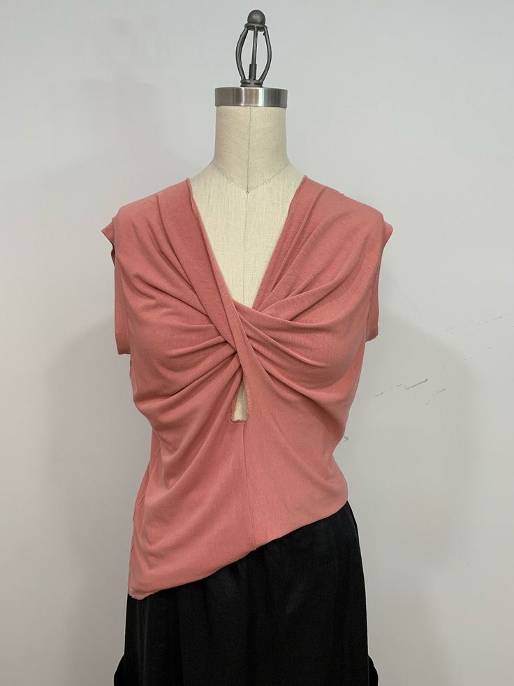 Sleeveless comfortable twist top made out of pink knit fabric. The front twist gives the top a very flattering look.  The T-shirt feels very soft to the touch and looks very elegant. It can be worn with any skirts or jeans. Bust  38 inches  Length  25 inches Fits  M Summer V-neck Top With Knot Detail, Summer V-neck Twist Front Tops, Stretch V-neck Top With Twist Front, Stretch V-neck Twist Front Top, Chic Stretch Pink Knit Top, Stretch Twist Front V-neck Top, Versatile Pink Stretch Tank Top, Pink Fitted Knit Top, Sleeveless Summer Top With Knot Detail