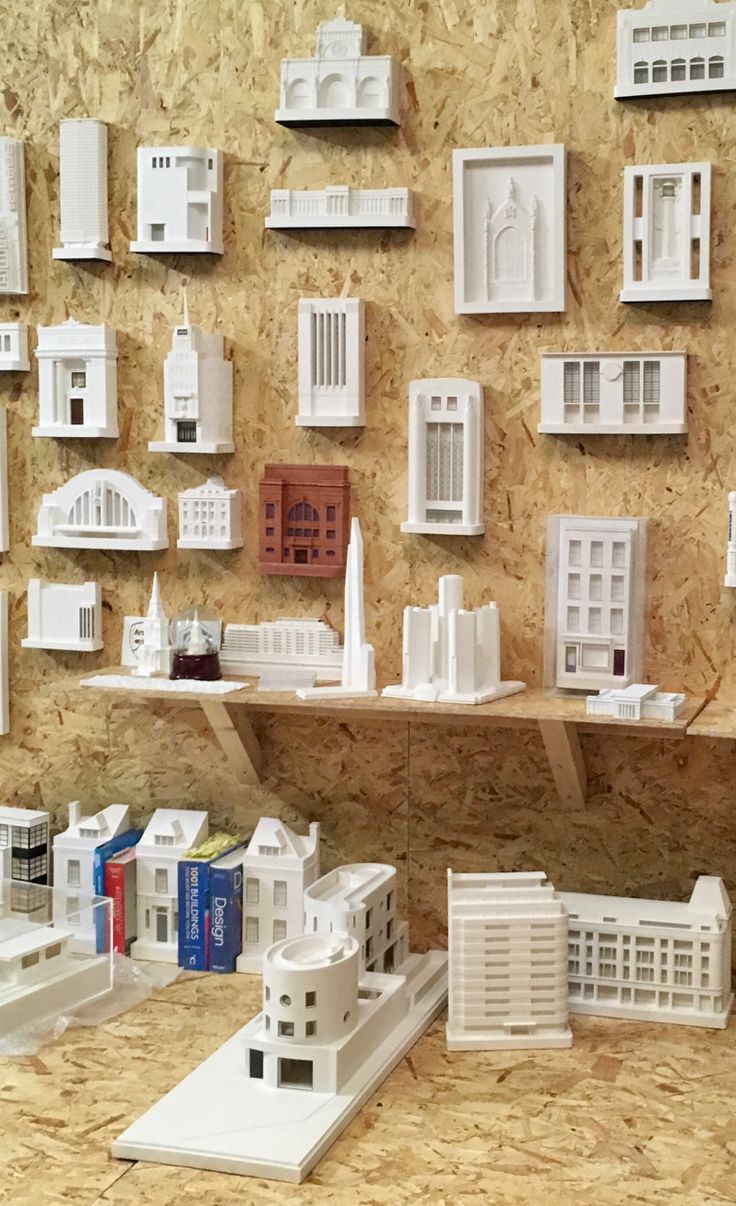 many white model houses and buildings are displayed on a wooden wall with plywood boards